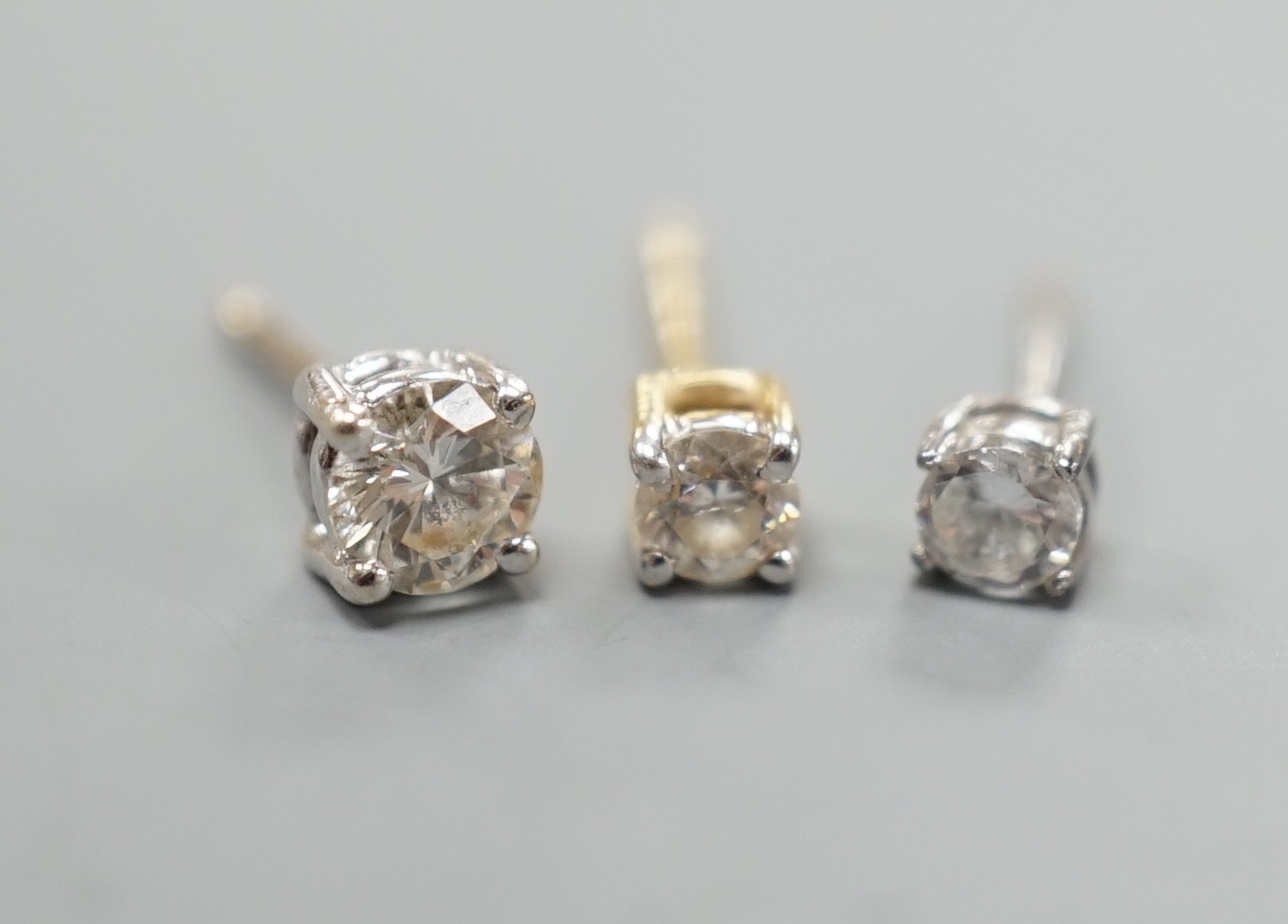 Two odd diamond set ear studs, the stones of various sizes and one paste set ear stud, gross weight 1.3 grams.